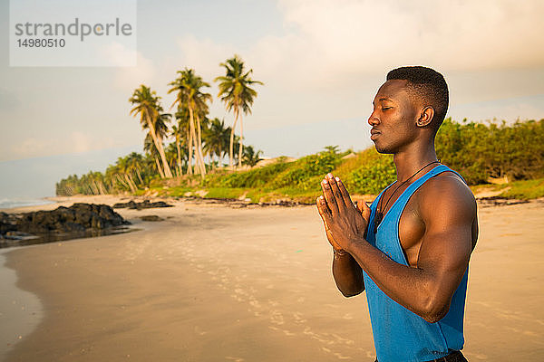 Mann praktiziert Yoga am Strand