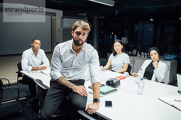 Mittelgroßer erwachsener Geschäftsmann vor dem Team bei einer Sitzung am Konferenztisch  Porträt