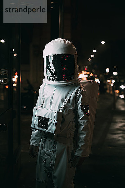 Astronaut geht nachts auf dem Bürgersteig