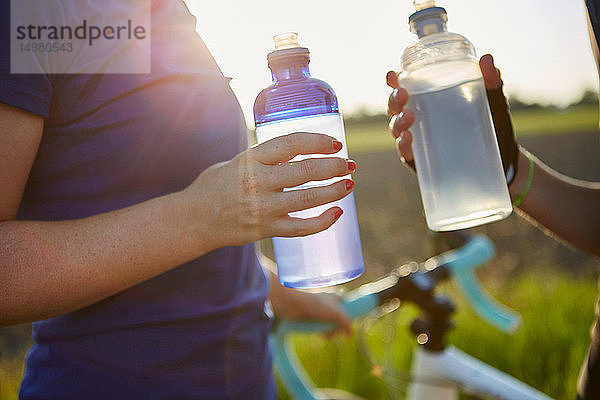 Zwei Radfahrerinnen mit Wasserflaschen in der Hand  Mittelteil