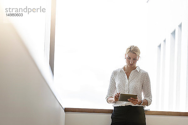 Geschäftsfrau benutzt digitales Tablett im Korridor