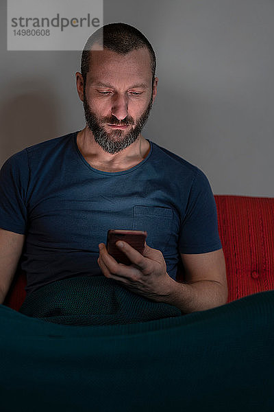 Hipster-Mann benutzt Smartphone auf dem Sofa