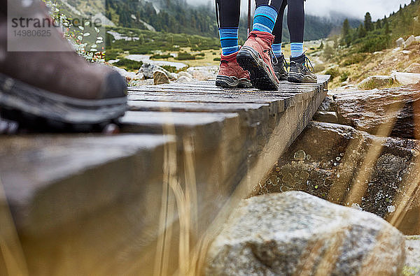 Wandererinnen  die über den Holzsteg wandern  Schrägansicht der Beine und Wanderschuhe