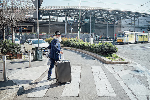 Leitender Geschäftsmann mit Rollgepäck auf einem Fußgängerüberweg  Mailand  Lombardei  Italien