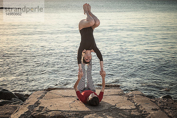 Frauen praktizieren Akro-Yoga am Meer