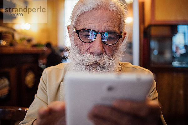 Leitender Geschäftsmann benutzt digitales Tablett im Café