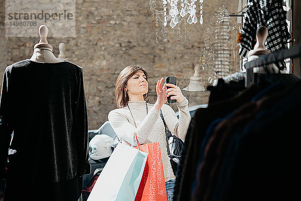 Weibliche Käuferin beim Fotografieren vor einer Modeboutique