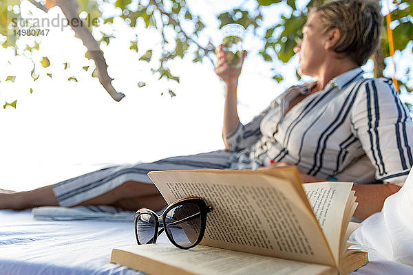 Frau liest Buch auf Schaukelbett am Strand  Insel Ginto  Linapacan  Philippinen