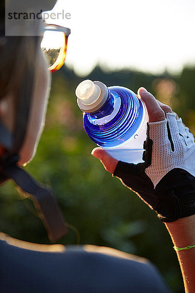 Radfahrerin  die aus einer Wasserflasche trinkt  über die Schulter gestürzt