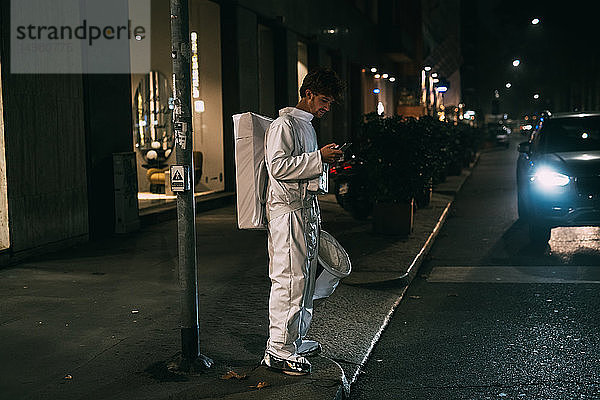 Astronaut mit Smartphone auf dem Bürgersteig