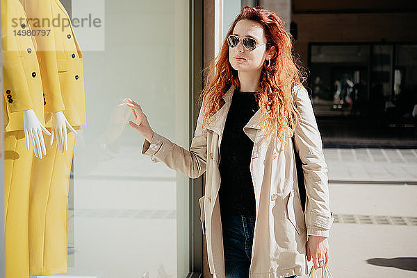 Frau schaut in Schaufenster einer Modeboutique