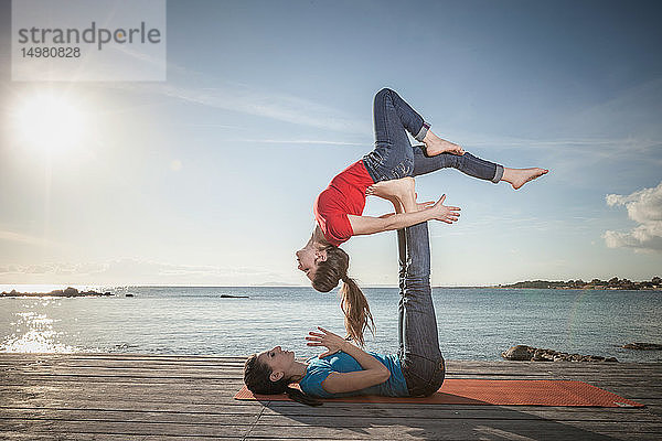 Frauen praktizieren Akro-Yoga am Meer