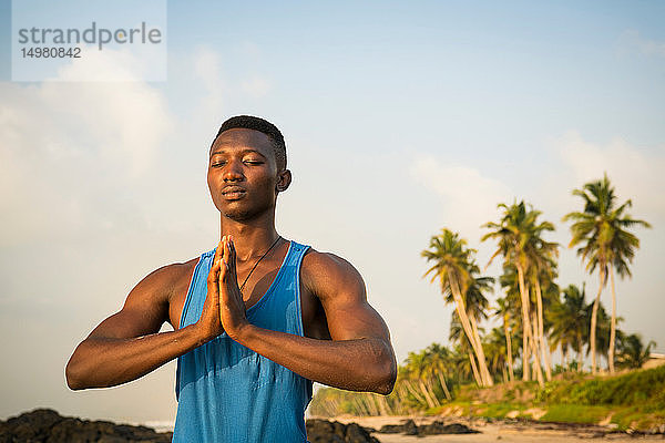 Mann praktiziert Yoga am Strand