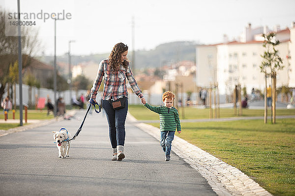 Mutter und Sohn gehen mit ihrem Welpen auf ruhiger Straße