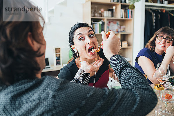 Mann füttert Frau bei Lunch-Party im Loft-Büro