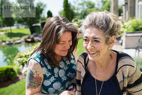 Frau lacht mit ihrer Mutter im Garten