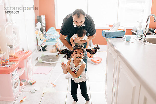 Mädchen spielt in der Küche vor dem Vater und dem kleinen Bruder  Portrait