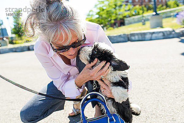 Ältere Frau streichelt süßen Hund im Park