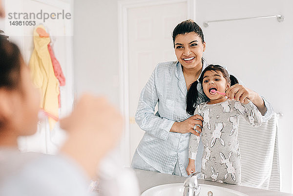 Mädchen mit Mutter beim Zähneputzen im Badezimmerspiegel  Blick über die Schulter