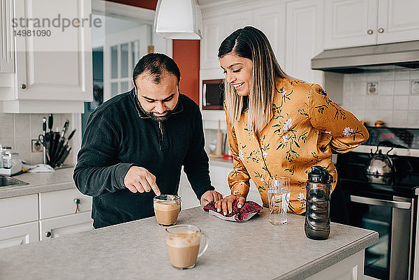 Mittleres erwachsenes Paar  das auf Kaffee auf der Küchentheke zeigt