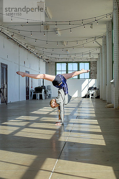 Teenagerin beim Handstand und Spagat im Tanzstudio