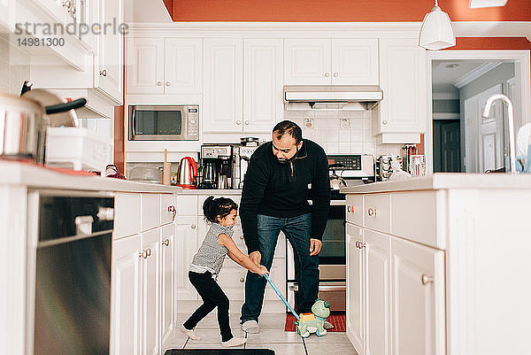 Mädchen spielt mit Schubspielzeug in der Küche  Vater schaut zu