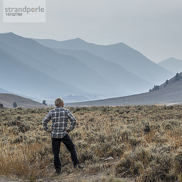 Älterer Mann steht auf einem Feld vor den Bergen in Sun Valley  Idaho  USA