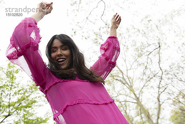 Lächelnde Frau im rosa Kleid tanzt