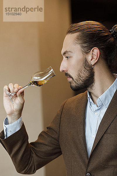 Junger Mann riecht an Wein im Glas bei einer Verkostung