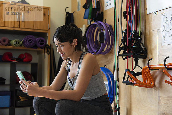 Frau benutzt Smartphone im Fitnessstudio