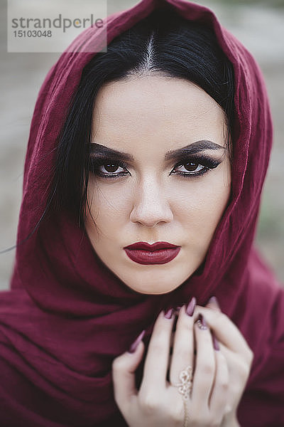 Porträt einer jungen Frau mit rotem Lippenstift und Kopftuch