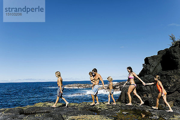 Familie spaziert auf Felsen am Meer