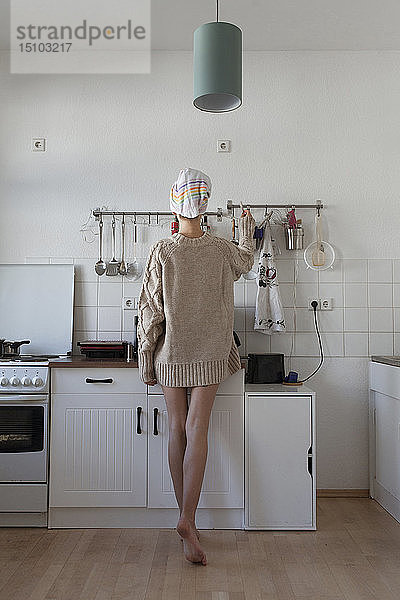 Rückansicht einer jungen Frau in der Wohnküche