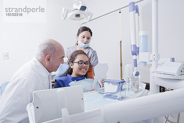Patientin lächelt in den Spiegel einer Zahnarztpraxis