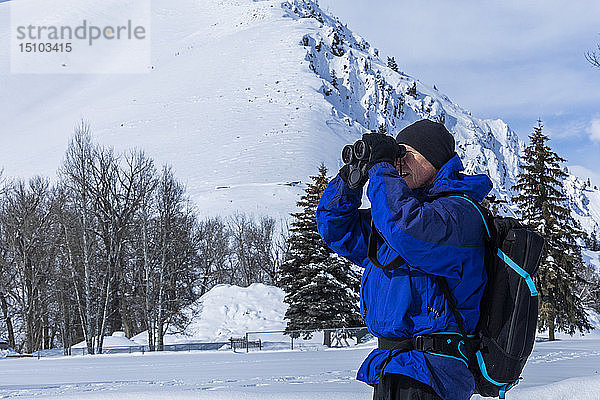 Älterer Mann mit Fernglas an einem schneebedeckten Berg in Sun Valley  Idaho  USA