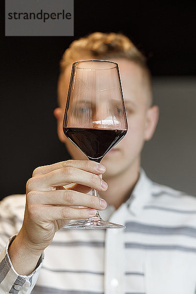 Junger Mann begutachtet ein Glas Wein