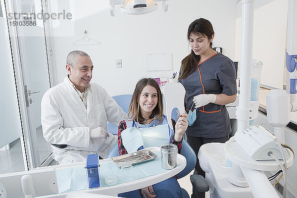 Patientin lächelt in den Spiegel einer Zahnarztpraxis