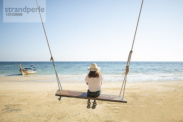 Junge Frau auf einer Schaukel am Strand