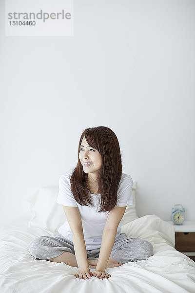 Junge japanische Frau im Bett am Morgen