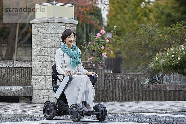 Japanische Seniorin im elektrischen Rollstuhl