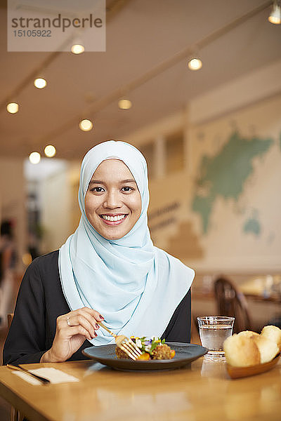 Junge südostasiatische Frau beim Essen im Restaurant