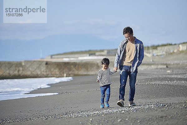 Japanisches Kind mit Vater am Strand