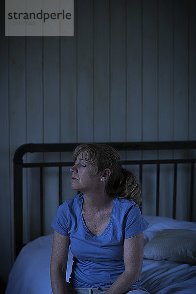 Traurige reife Frau sitzt auf dem Bett