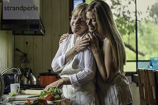 Tochter  die ihre Mutter in der Küche umarmt