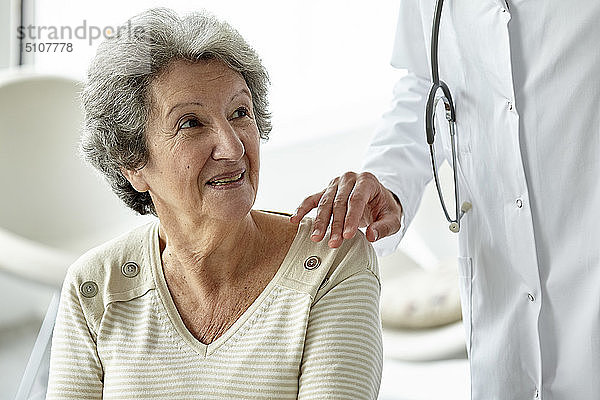 Arzt tröstet ältere Frau