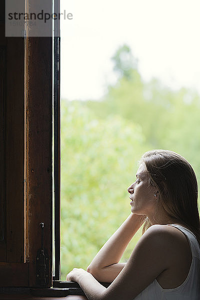 Frau schaut durch das Fenster