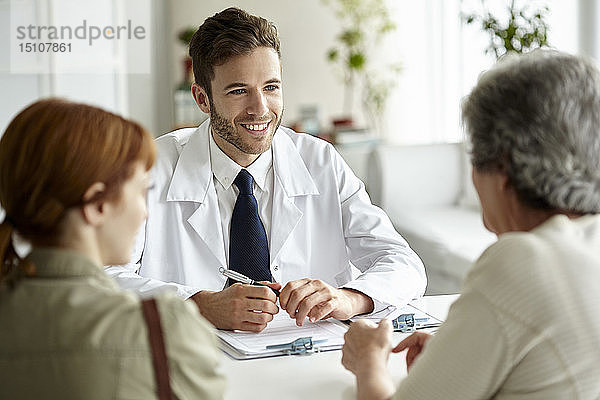 Lächelnder Arzt im Gespräch mit einem älteren Patienten