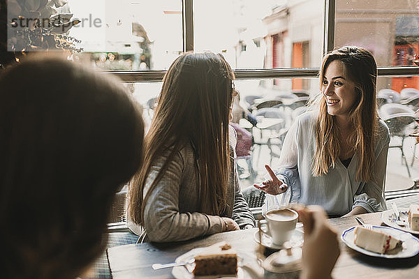 Drei glückliche junge Frauen treffen sich in einem Café