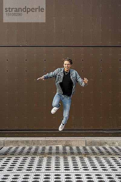 Junger Mann springt vor eine Mauer