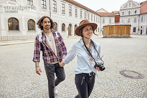 Junges Touristenpaar beim Spaziergang im Innenhof der Münchner Residenz  München  Deutschland